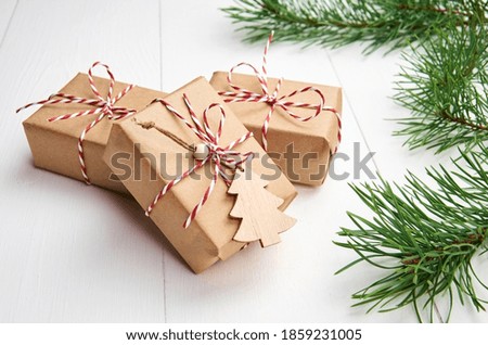 Christmas gift boxes with pine tree branches on white wooden background