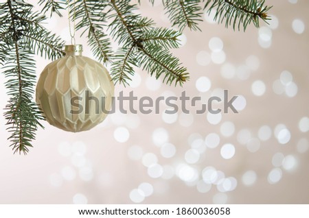 White ball hangs on a Christmas tree branch. Bokeh. Christmas decoration