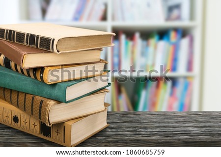 A stack of books on a black table. Library in the background.