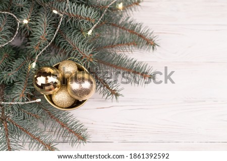 Stylish bucket of Christmas Golden toys on a white wooden background and branches of Christmas trees