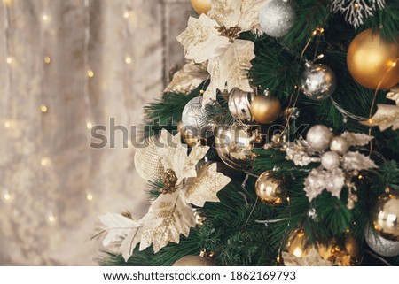 Gold and silver Christmas toys, balls garlands on a spruce branch with copy space.