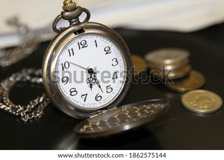 Elegant handheld vintage pocket clock with coins in office place