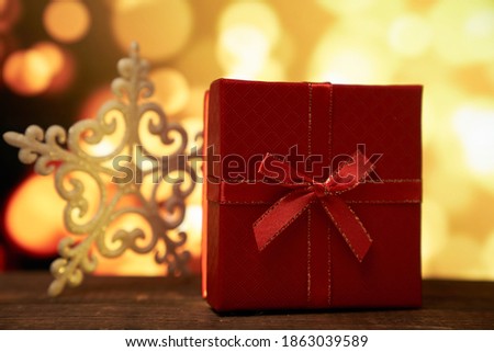 New year's red gift with a bow on a brown wooden table on a gold bokeh background with a copy space
