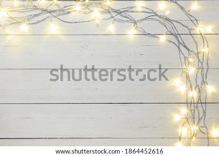 Christmas background with garland lights on natural white wooden boards. Copy space.