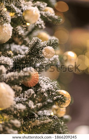 Close up view of gold christmas balls on Christmas tree bright bokeh and snow. Xmas Holiday concept. Decorative coniferous plant. Stylish Christmas Outdoor decorations. Festive decor. Copy space.