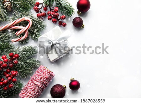 Christmas tree branches with red baubles on white background. Border, top view, flat lay