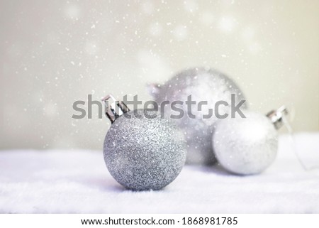 Christmas background. Silver-colored Christmas balls on a grey background sprinkled with snow. Space for text, side view.