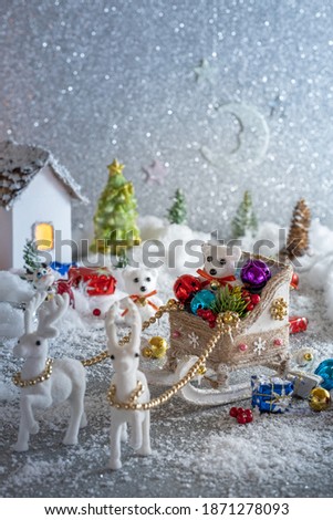 Christmas fabulous composition. Polar bear in a Christmas sleigh with gifts and toys on the background of houses and fir trees in the snow