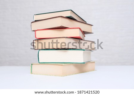A stack of books lying on a white table, reading and education concept.