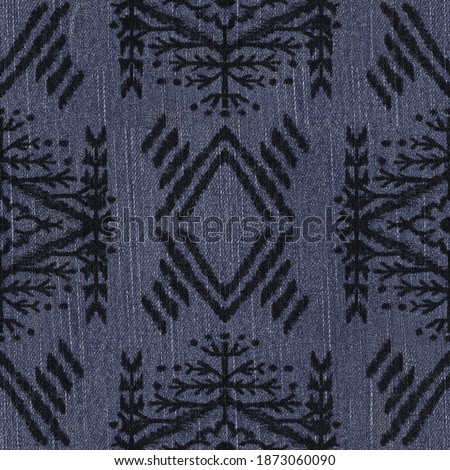 Seamless tribal ethnic rug motif pattern on dark denim texture. High quality illustration. Boho gypsy folk art style motif on seamless jean texture. Repeat raster jpg pattern swatch.
