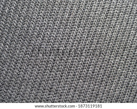 Background, texture, surface of wool knitted fabric from yarn, closeup. Image for the background, wallpaper. wool carpet or sweater. Gray texture. Modern design.
