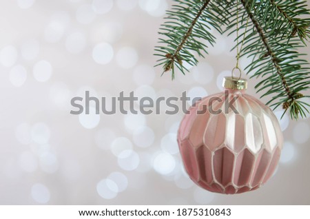 A pink ball hangs on a Christmas tree branch. Bokeh. Christmas decoration