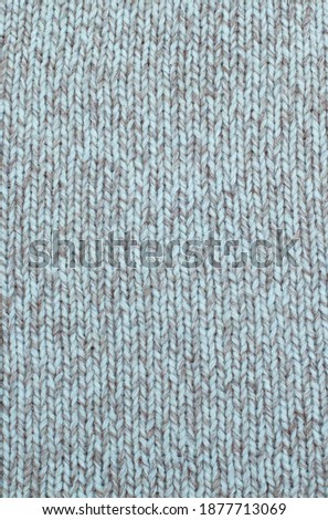 Wool knitting fabric in light gray and beige, hand, plain knitting. Vertical photo