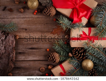 Gift box with red silk bow among Christmas decorations on a wooden table. Merry Christmas and Happy New Year background with empty space for text.
