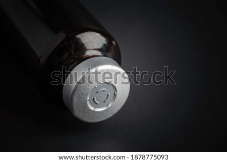 A macro shot with selective focus of an amber color vaccine injection bottle set on a dramatic black background.
