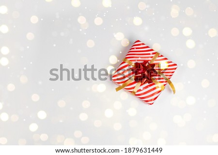 Gift box with red bow on a white board with festive golden glitter. Flat lay, top view