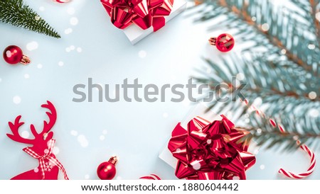 Holiday Christmas background. White gift box with red ribbon, New Year balls and winter tree in xmas composition on white for greeting card. Copy space. Winter holidays, New Year.