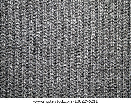 Background, texture, surface of wool knitted fabric from yarn, closeup. Image for the background, wallpaper. wool carpet or sweater. Gray texture. Modern design.