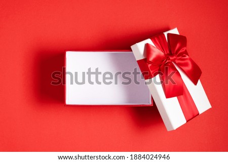White open gift box with red bow on red background. Valentine day, birthday, Christmas, concept, design. Flat lay, top view, copy space