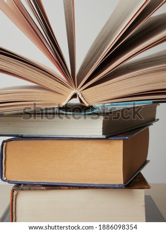 Education learning concept with opening book or textbook in old library, stack piles of literature text academic archive on reading desk and aisle of bookshelves in school study class room background 