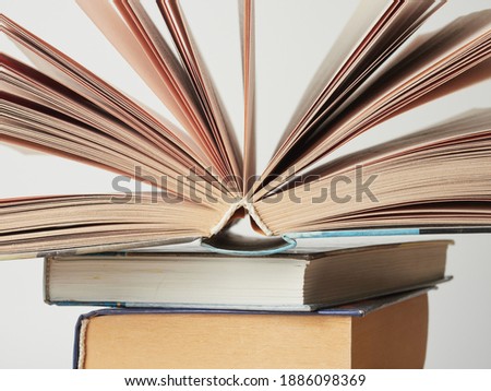 Education learning concept with opening book or textbook in old library, stack piles of literature text academic archive on reading desk and aisle of bookshelves in school study class room background 