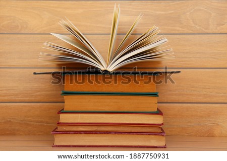 Stack of books with opening book  on wooden background. 