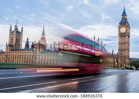 A fast moving double-decker bus crosses Westminster Bridge in London at sunrise.