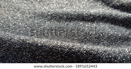 Black shiny fabric with machine knitting and lurex, in folds (texture).