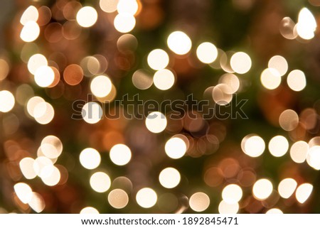 Abstract holiday bokeh background. Blurred lights of garland hanging on Christmas tree. Focus on foreground. Copy space for your text and decorations.