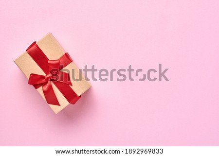 Beautiful gift box with red ribbon on a pink background wall. Valentine day greeting card. Top view.