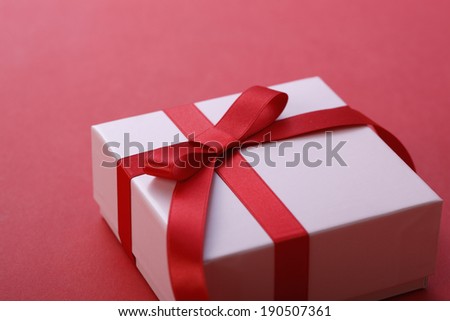 A gift box wrapped up with a red ribbon