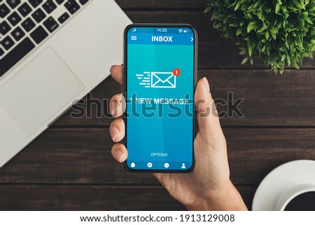 Woman Holding Phone With New E-Mail Message Inbox Sitting At Desk In Modern Office. Email Notification, Online Communication Application. Above View, Cropped, Closeup