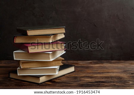 a stack of vintage old reading books on a wooden table copy space