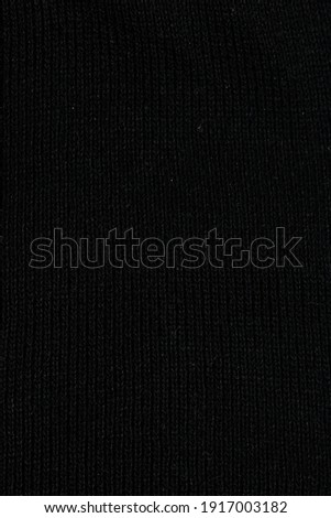black fabric surface, small stitches as background. Structure of dark fabric as pattern backdrop.