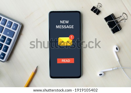 New message concept on smart phone screen on wooden desk. Flat lay