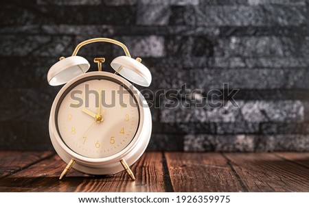 White vintage alarm clocks on old wooden table and dark rock  background wall.