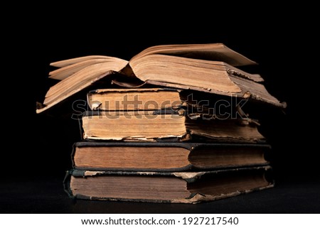 A stack of old books on the desk. Old extensive literary publications. Dark background.