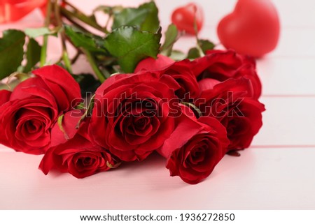 Beautiful red roses on pink table, closeup. Valentine's Day celebration