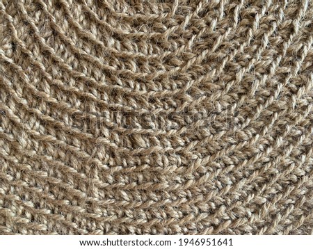 Close up photograph of brown, beige wicker surface, wicker basket, straw bag, straw hat. Detailed dark yellow wire mesh texture. Natural beige wool background. 