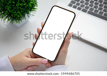 female hands holding golden phone with isolated screen over white table in office 
