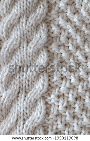 Background from beautiful, knitted background, Aran pattern, weave from braids. Concept handicrafts, DIY, leisure, fashionable warm clothes, hobbies. Top view, macro, close-up, flat lay. Vertical.