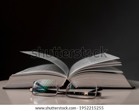 Eyeglasses and open book on black background. Education concept.
