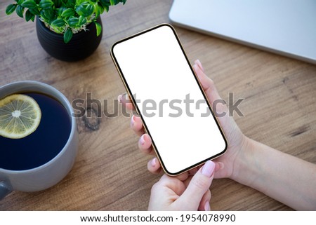 female hands holding golden phone with isolated screen over wooden table in office 