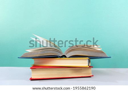 World Book Day. There is a stack of books on the table, with an open book on top. Turquoise background. The concept of education and reading.
