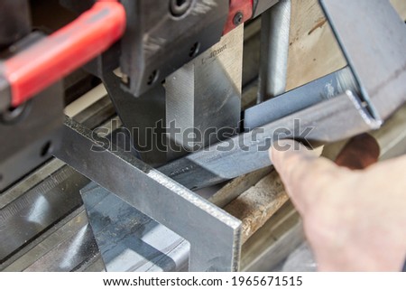worker holding a metal part on sheet bending machine