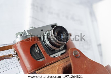 old film camera with a case lies on the background of paper documents. Web banner.