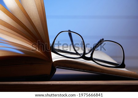 Glasses lying on a book on blue background        