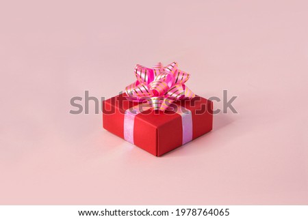 One red gift box on pink background.
