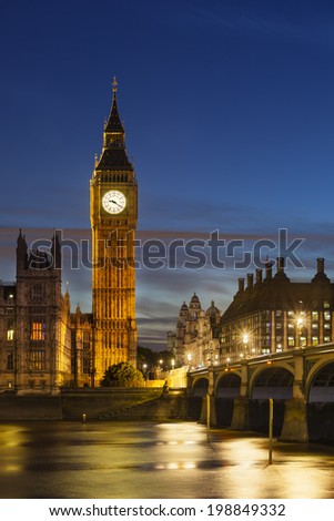 Long exposure night shot of the Houses of Parliament in London with blue sky and the Westminster Bridge in the foreground.