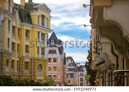 Facade of multicolored modern houses. A cobblestone European cosy street in perspective. An urban city street with parked cars on a side of a road at summer day. Modern colorful architecture. Building